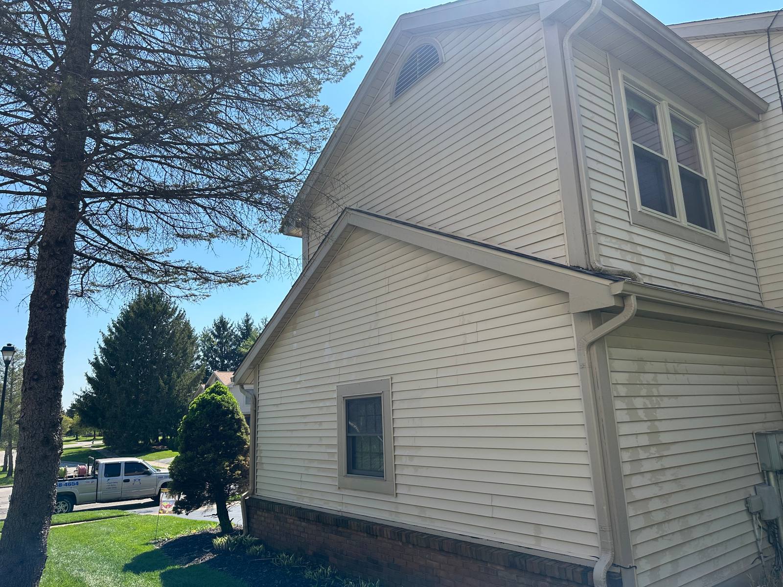 Two-story Sylvania home gable after soft washing — clean tan siding