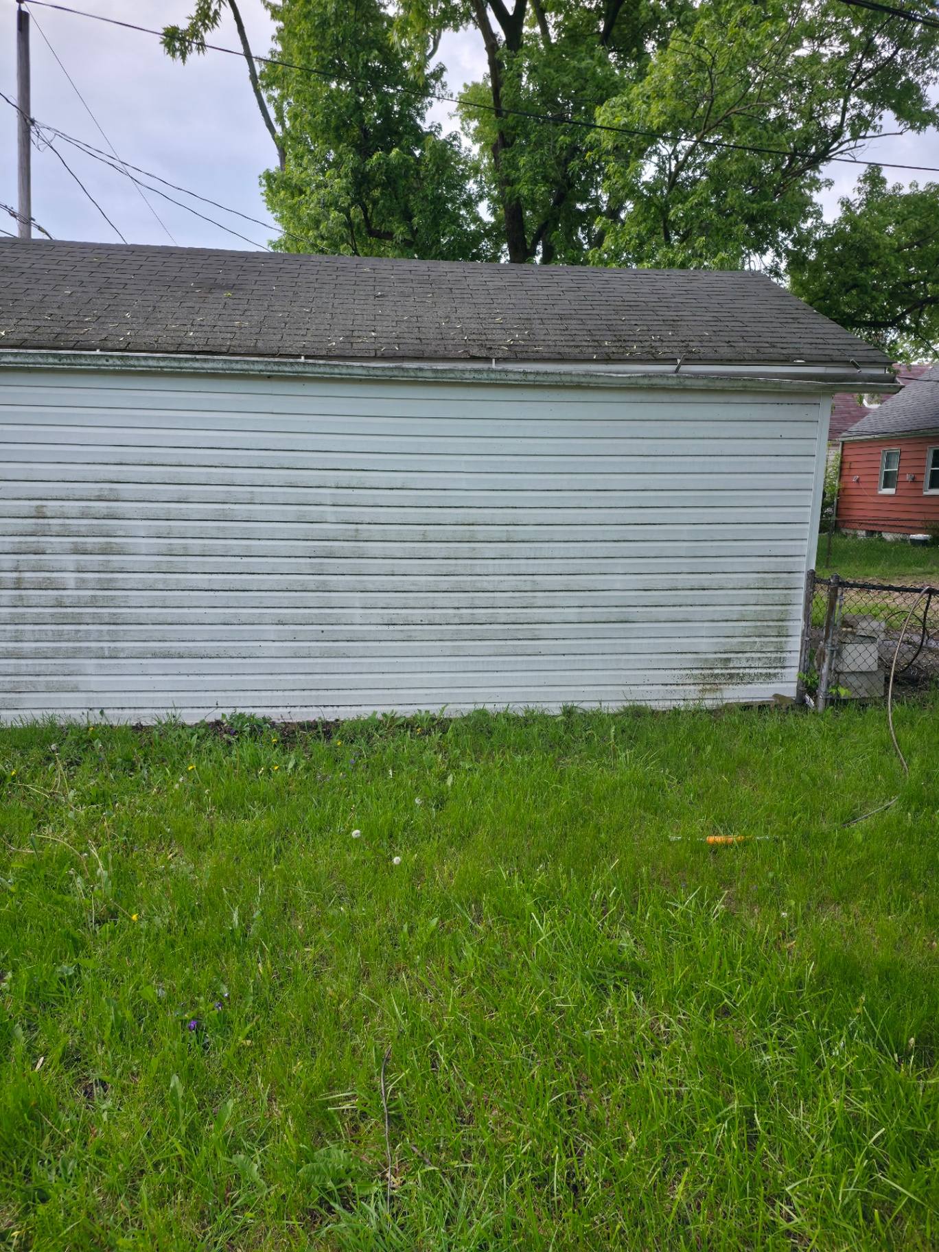 Garage siding before soft washing showing green algae and grime on white panels