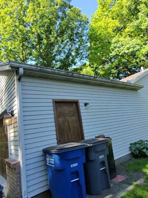 Side of garage before soft washing with dirt, mildew, and grime built up on white siding
