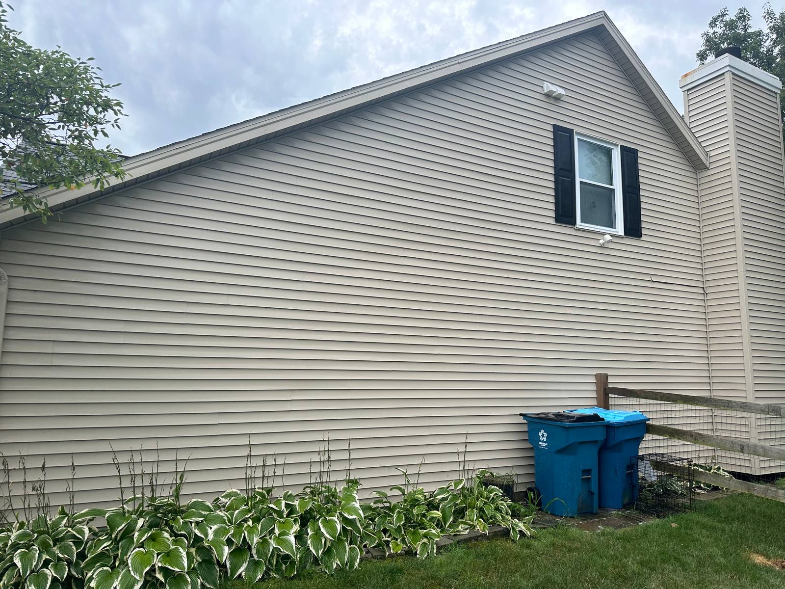 Home gable end after soft washing — restored tan siding free of algae and streaks