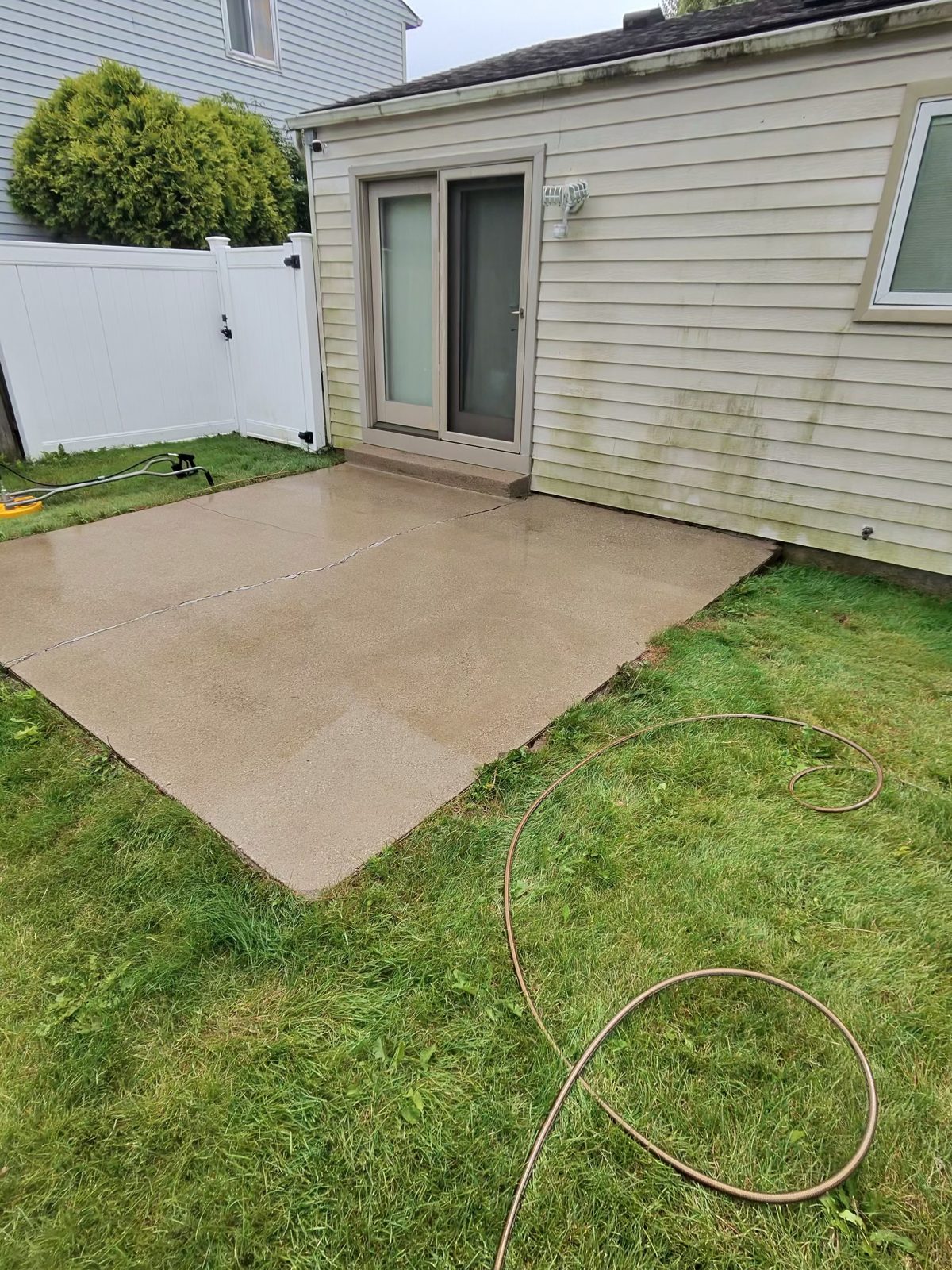 Backyard concrete patio after pressure washing — bright clean concrete restored