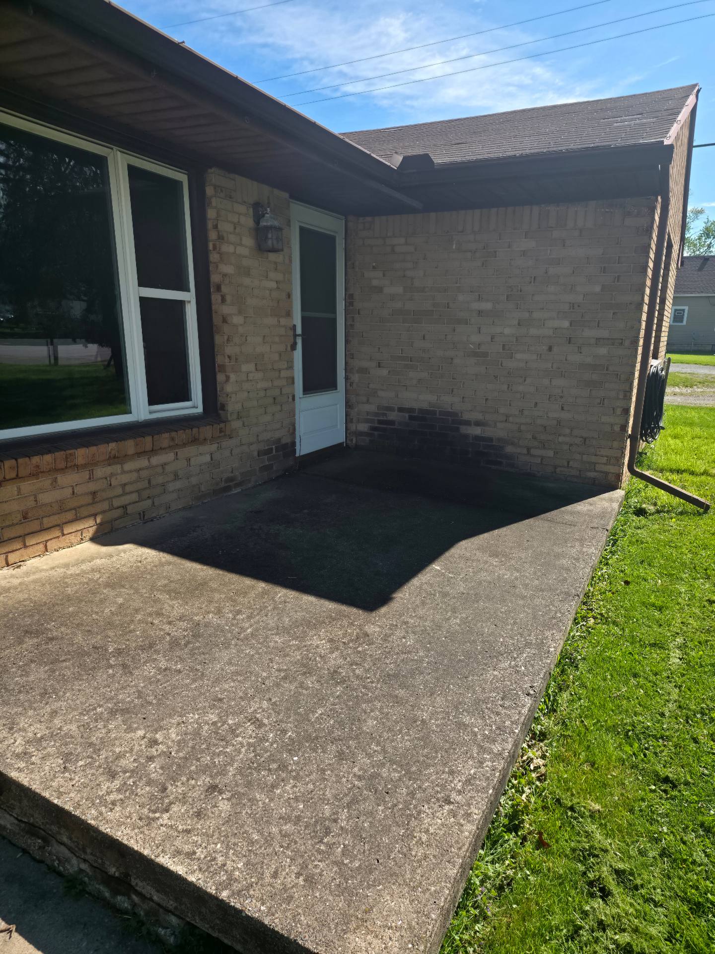Sylvania OH backyard patio before pressure washing — stained concrete and dirty brick